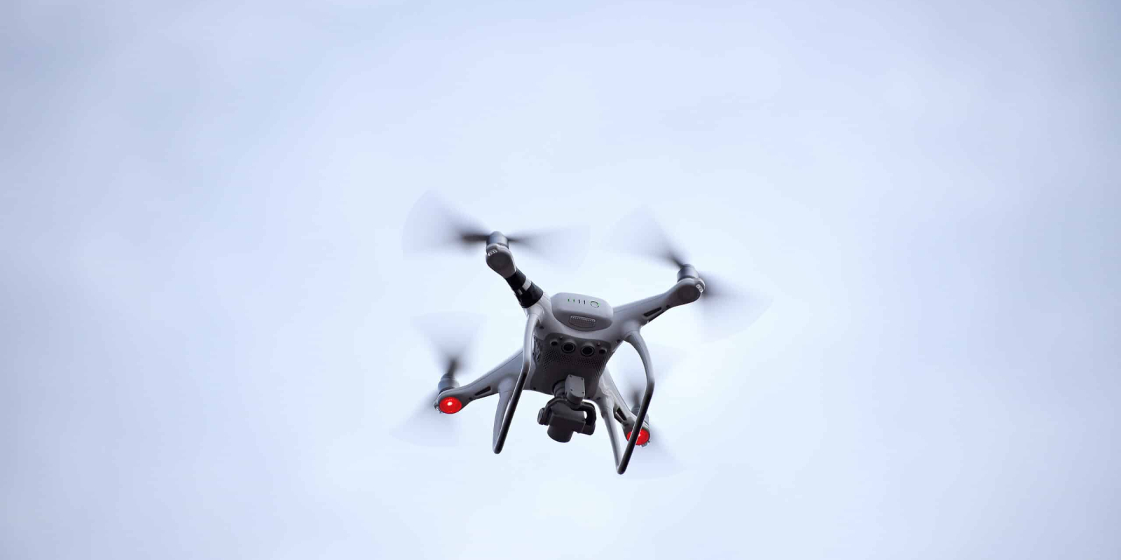 Close up low angle view of one surveillance aerial photography quadcopter UAV drone flying in sky, copy space