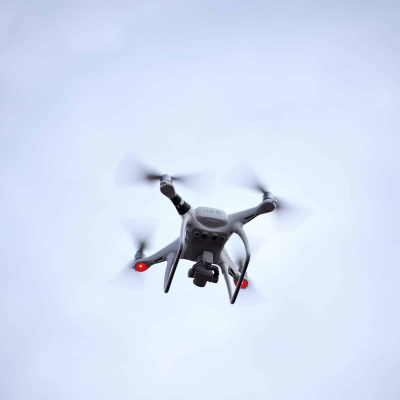 Close up low angle view of one surveillance aerial photography quadcopter UAV drone flying in sky, copy space